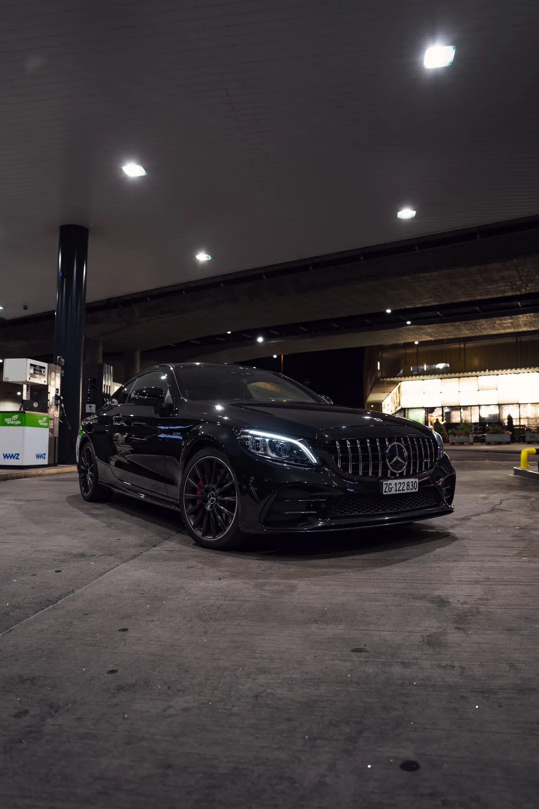 Schwarzer Mercedes-AMG C 43 nachts an der Tankstelle, von vorne