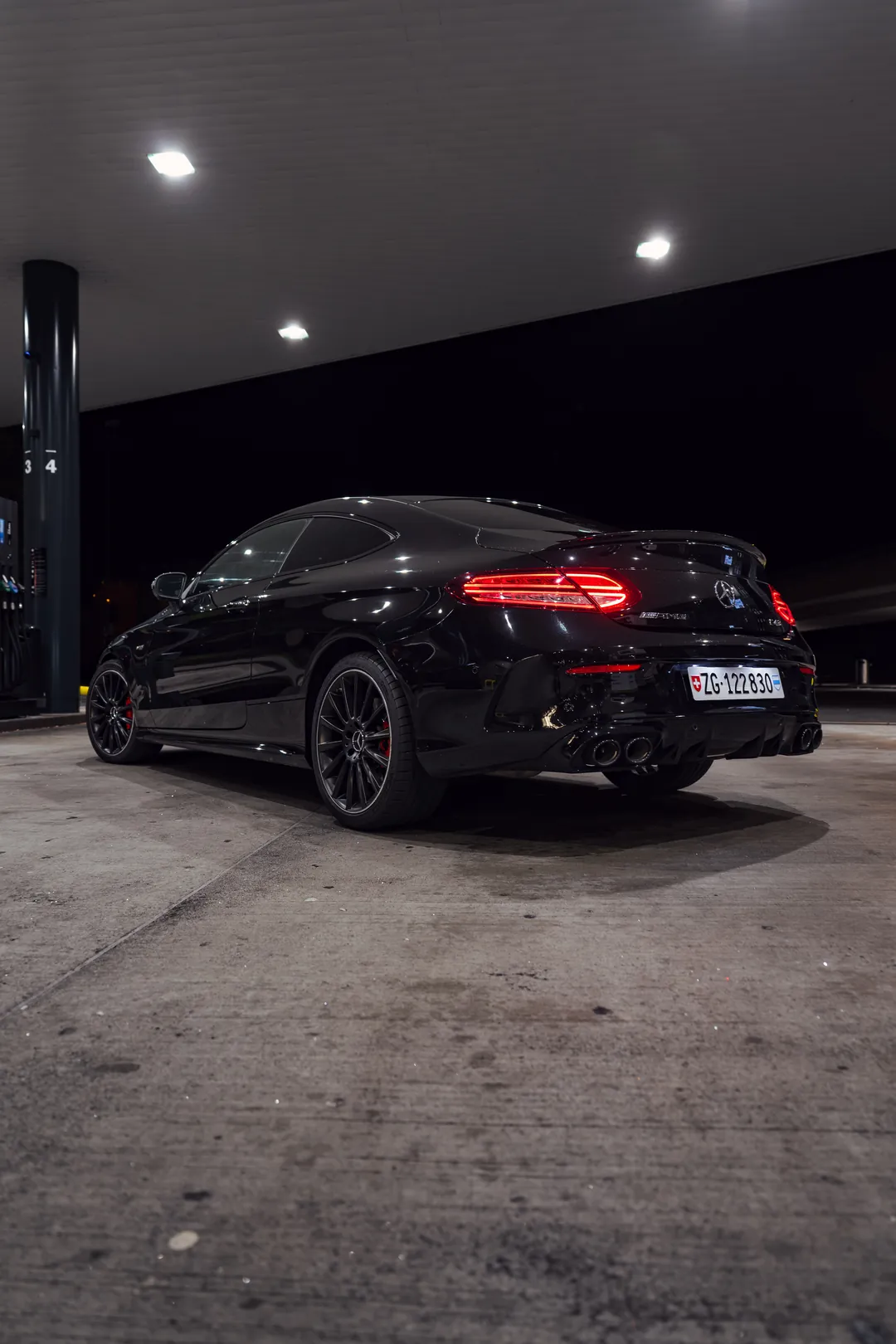 Schwarzer Mercedes-AMG C 43 nachts an der Tankstelle, von hinten